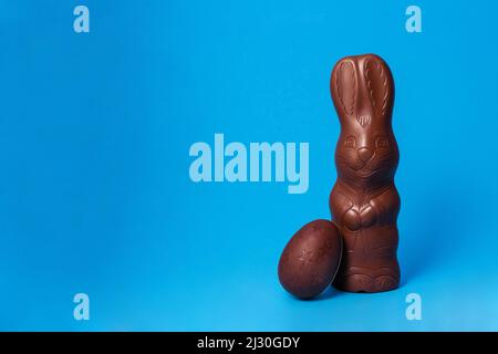 Easter Chocolate Bunny with egg on Blue Background Creative Easter Holiday Concept.jpg Stock Photo