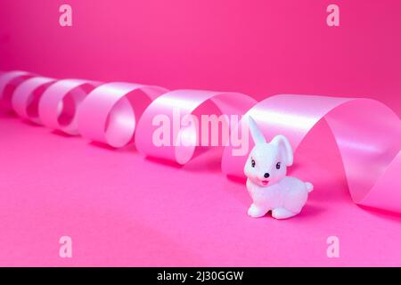 Little white rabbit and pink ribbon backgroung Stock Photo