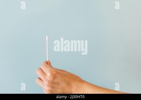 Hand holds Covid-19 PCR nasal swab against background with copy space Stock Photo