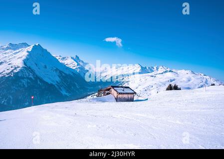 Log cabin on snow covered mountain during winter Stock Photo