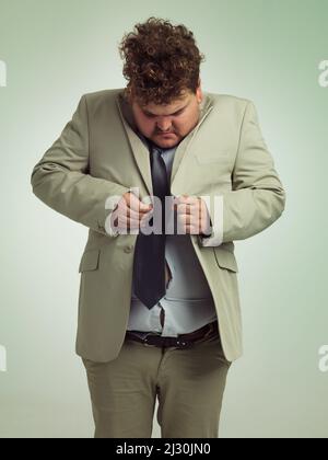 How is this done. Shot of an overweight man in a suit trying to button his jacket. Stock Photo