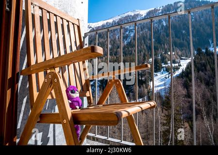 Soft plush toy enjoying sunlight on chair in balcony at resort Stock Photo