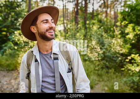 Laughing young man hiking in forest during summer trekking Stock Photo