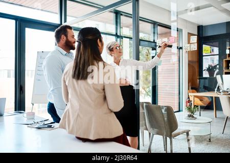 Brainstorming sessions thatll make a big difference. Shot of a group of businesspeople brainstorming with notes on a glass wall in an office. Stock Photo