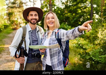 Young couple reading map while hiking in the woods during summer hike Stock Photo