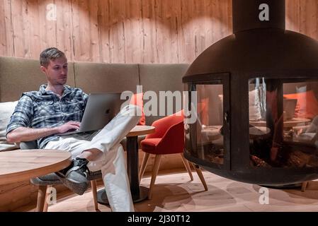 Relaxed man using laptop while waiting in luxurious hotel lobby Stock Photo
