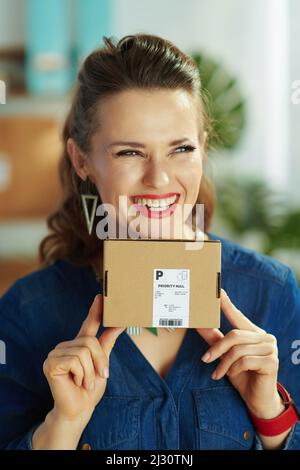 smiling stylish middle aged small business owner woman with parcel in the office. Stock Photo