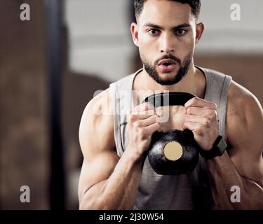 Dont count the days, make the days count. Shot of a young man doing squats with weights in gym. Stock Photo