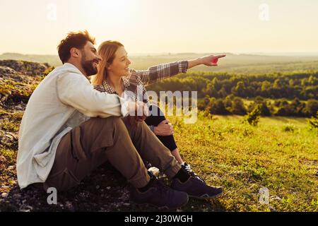 Young couple sitting together watching  countryside landscape during summer hike in Jura, Poland Stock Photo