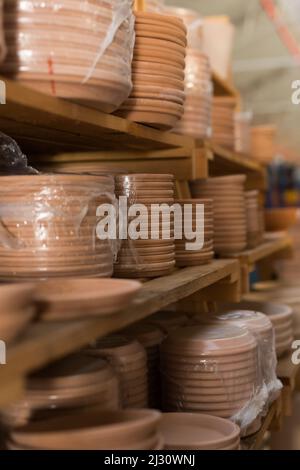 Clay plates for flower pots in stretch film on shelves in store Stock Photo