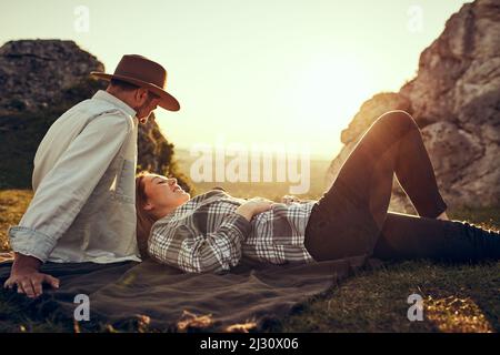 Young heterosexual couple relaxing in mountains lying on blanket during sunny summer day Stock Photo