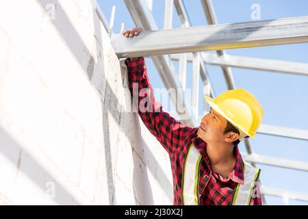 Construction worker or contractor checking house frame, worker roofer builder working on steel roof structure on building  construction site Stock Photo