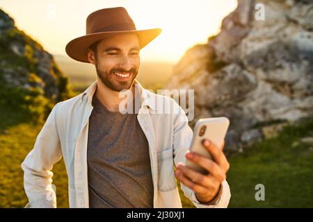 Young man using smartphone during summer hike in mountains Stock Photo