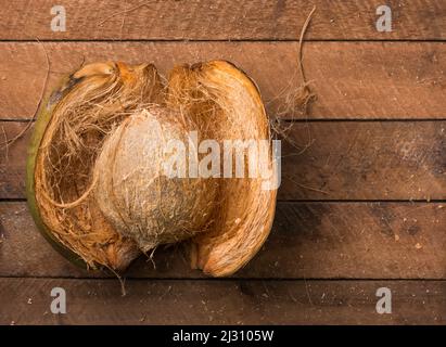 open coconut with husk, healthy tropical fruits on a wooden table top, taken from above with copy space Stock Photo