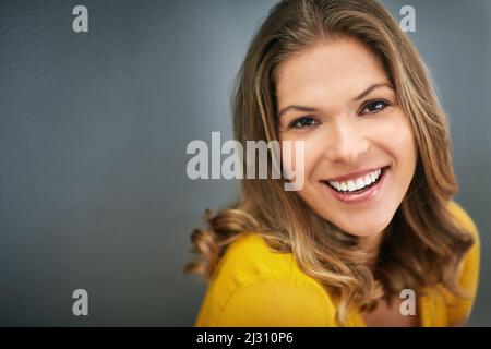 The power of confidence is limitless. Shot of a young woman posing against a gray wall. Stock Photo