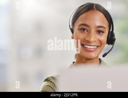 Im ready to make your day. Shot of a call centre agewnt smiling while sitting at her desk. Stock Photo