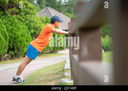 Man athlete doing workout, stetching his arms at a park. Stock Photo