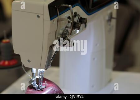 Industrial double needle leather sewing machine in a shoe factory. Selective focus. Stock Photo