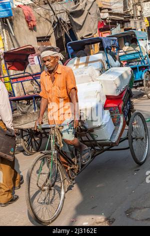 DELHI, INDIA - NOV 11, 2011: old rickshaw man has his rickshaw loaded with freight in Old Delhi, India. Stock Photo