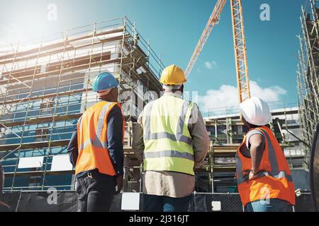 Creating thriving communities one building at a time. Shot of a group of builders assessing progress at a construction site. Stock Photo