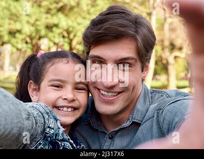 Never forget a single moment. Shot of a happy young man taking a selfie with his adorable daughter in the park. Stock Photo
