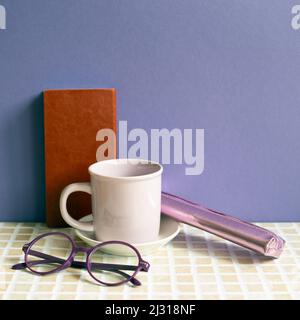 Notebook and coffee cup, glasses, pencil case on desk. purple wall background. workspace Stock Photo