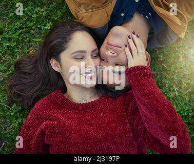With you next to me, life is complete. High angle shot of a happy young couple laying together on the grass. Stock Photo