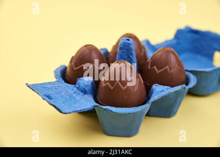 Chocolate eggs in blue box on yellow background with cope space, Happy Easter Stock Photo