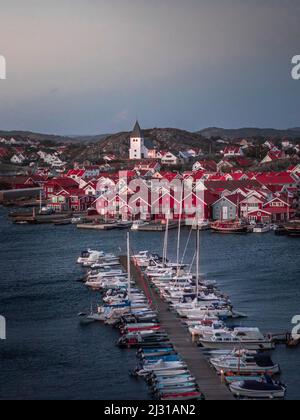 Red houses with church and boats in the harbor in the village of Skärhamn on the archipelago island of Tjörn on the west coast of Sweden, in the evening Stock Photo