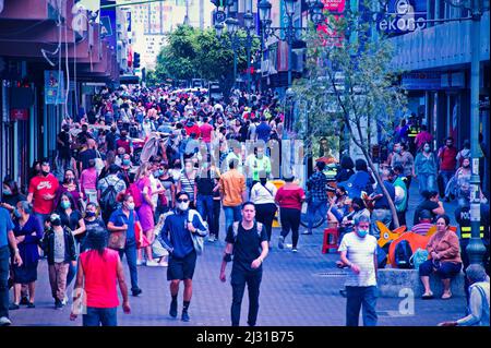 Crowd of anonymous people walking down the sidewalk with bright ...