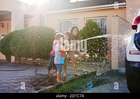 This car is going to be squeaky clean. Shot of a family washing their car in the driveway. Stock Photo