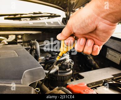 Mechanic hand pulling up oil dipstick of the car engine for checking oil level Stock Photo