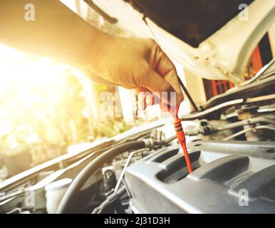 Mechanic hand was pulling oil dipstick to lube level checking of engine car Stock Photo