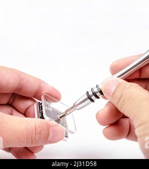 Electronic technician removing metal nut with a precision screwdriver for electronic repair on white background Stock Photo