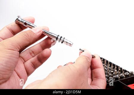Hand is removing the precision screwdriver component for replacing the cross head of precision screwdriver,isolated on white background Stock Photo