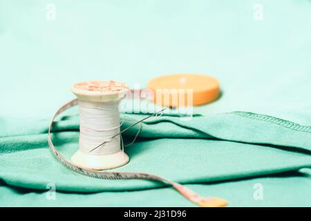 Spool of thread and sewing needle,measuring tape on the cotton cloth material Stock Photo