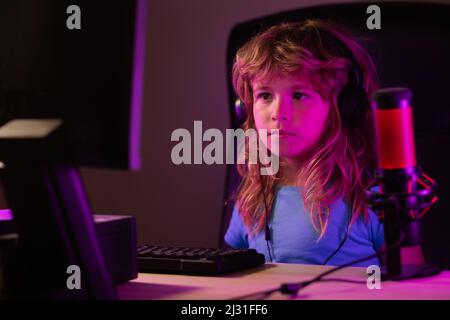 Child plays a video game on the pc computer screen. School, study, online learning concept. Gamer play computer games. Neon lighting. Stock Photo