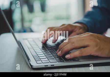 man using computer laptop searching internet, sending sms, using text messenger or online banking. Stock Photo