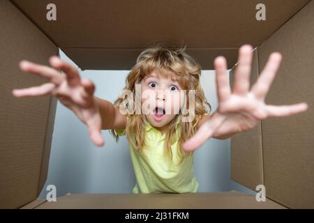 Surprised cute child opening a present. Cardboard boxes, parcels. Delivery service concept. Parcel packaging or unpacking concept. Stock Photo