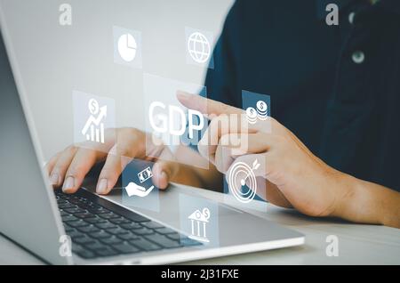 man hand using laptop to working technology and business concept.GDP Gross Domestic Product icons and symbols virtual screen. Stock Photo