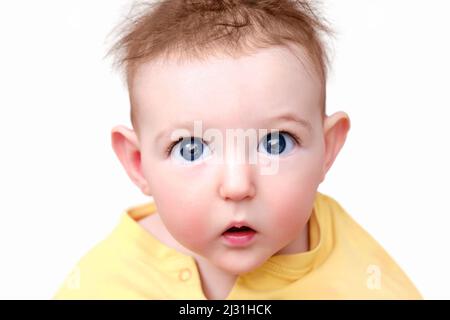 Surprised infant baby boy with big eyes on a white background, isolated. Portrait of a frightened child with a messy hairstyle Stock Photo