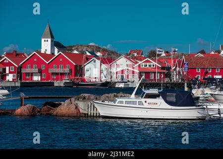 Red houses with church and boats in the village of Skärhamn on the archipelago island of Tjörn on the west coast of Sweden, blue sky with sun Stock Photo