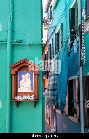 Madonna shrine with floral decorations on colorful house facade, fishing island Burano, Venice, Veneto, Italy, Europe Stock Photo