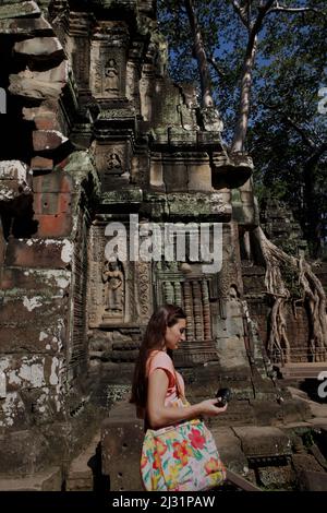 A woman visitor is photographed as she is walking in front of a temple in the temple compound of Ta Prohm in Siem Reap, Cambodia. Stock Photo
