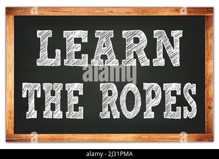LEARN THE ROPES written on black wooden frame school blackboard Stock Photo