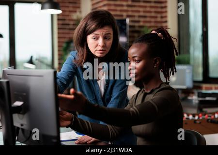 African american digital artist talking with team leader about design software. Multiracial employees in conversation about software developing technology and how to improve it. Stock Photo