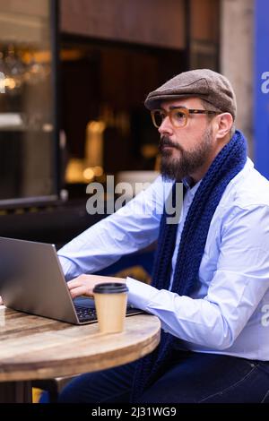 Thoughtful tourist using his laptop in outdoor cafe Stock Photo