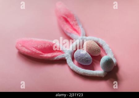 Bunny rabbit face made of bunny ears and colourful eggs on pink background. Easter minimal concept. Stock Photo