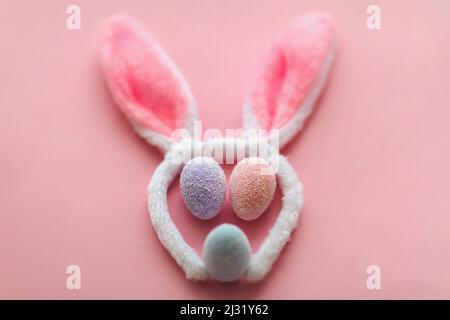 Bunny rabbit face made of bunny ears and colourful eggs on pink background. Easter minimal concept. Stock Photo