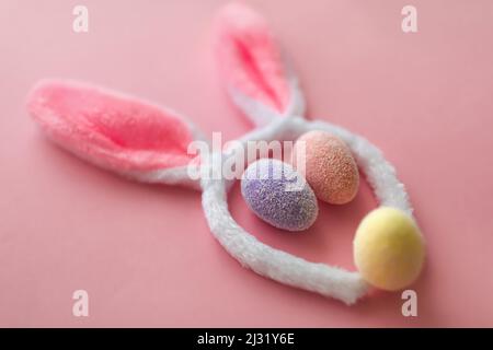 Bunny rabbit face made of bunny ears and colourful eggs on pink background. Easter minimal concept. Stock Photo